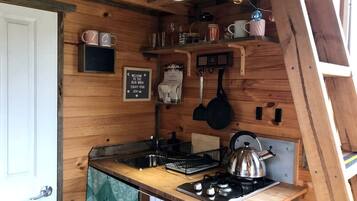 Une cuisine de taille réduite, équipée d’un évier, d’une cuisinière et d’ustensiles suspendus.