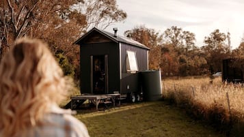 Eine kleine, eingeschossige Holzhütte mit einem Metalldach, einer Schiebetür und einer kleinen Veranda.