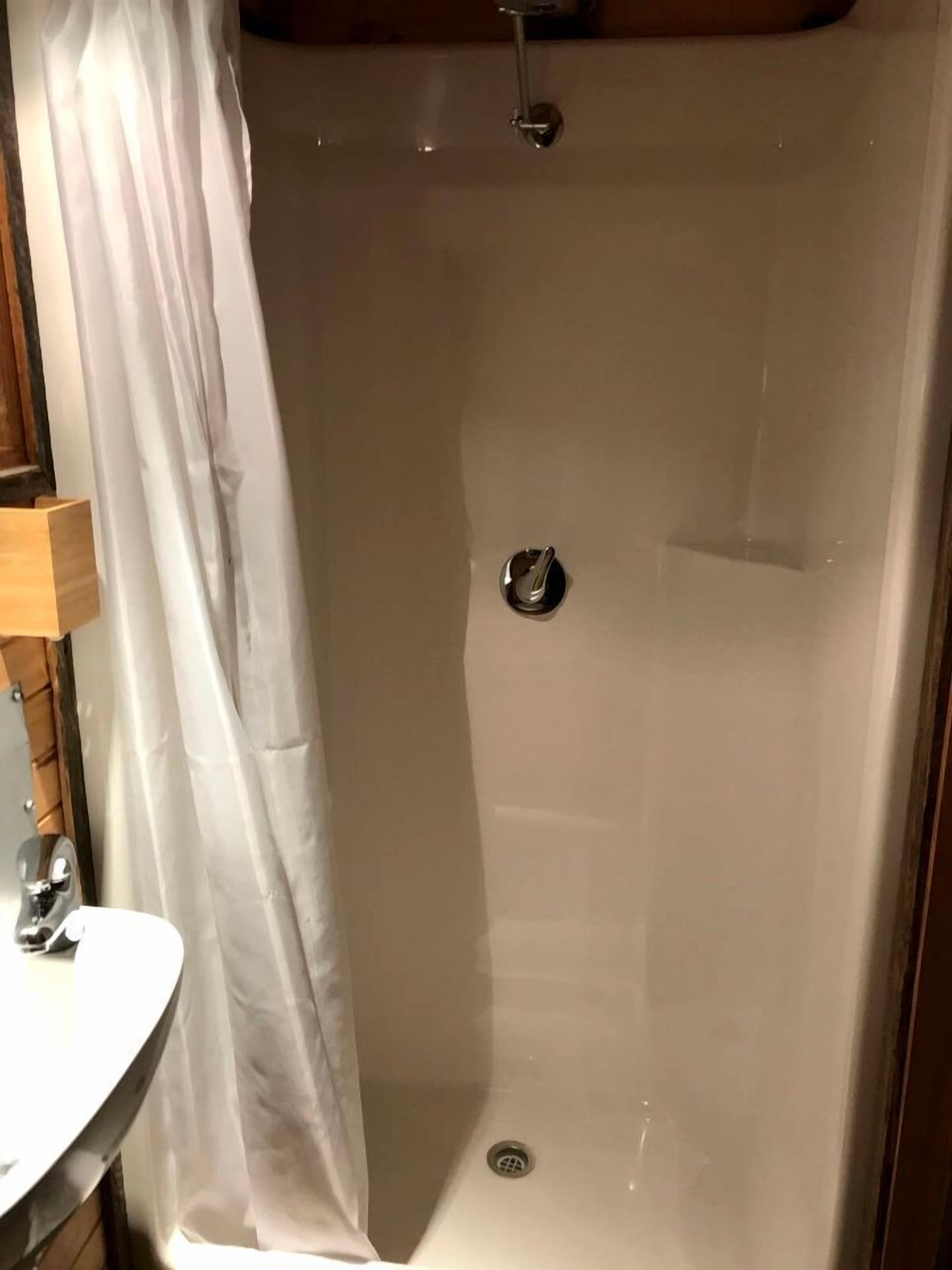 A shower with a curtain, a sink, and a mirror.