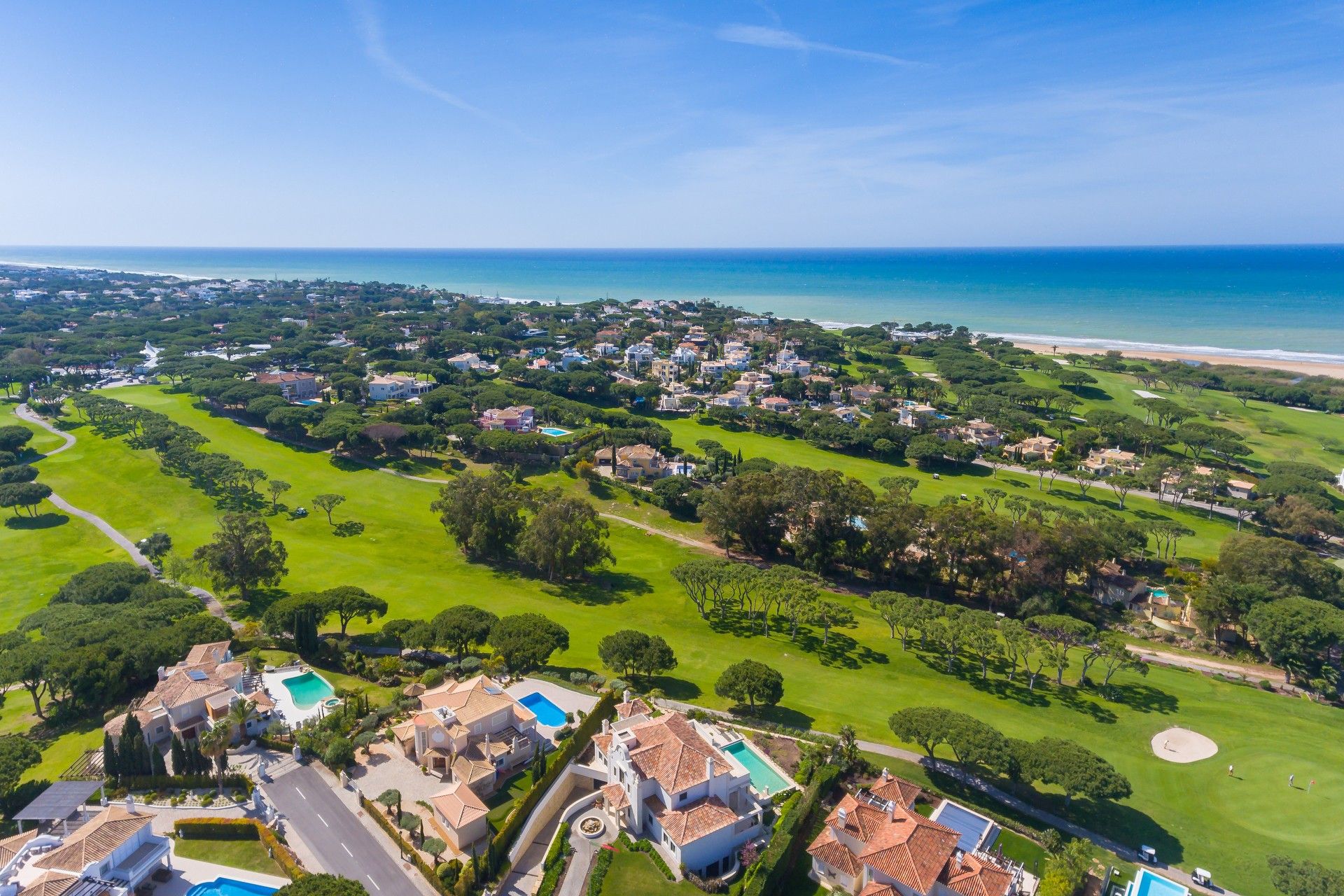 Vista aérea de una zona residencial costera con casas, áreas verdes y una playa.