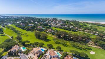 Vista aérea de una zona residencial costera con casas, áreas verdes y una playa.
