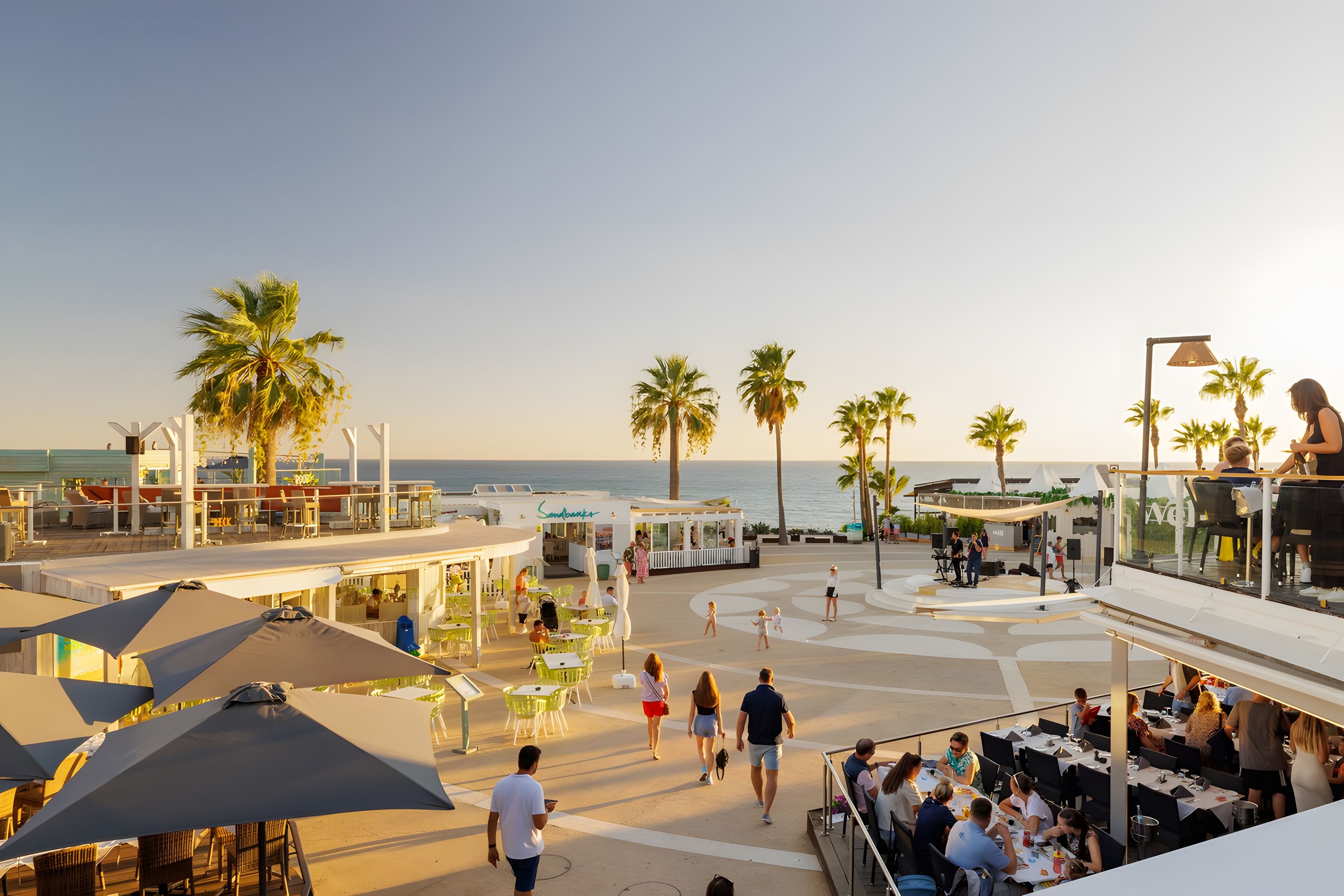 Un resort sulla spiaggia con posti a sedere all'aperto, palme e vista sull'oceano.