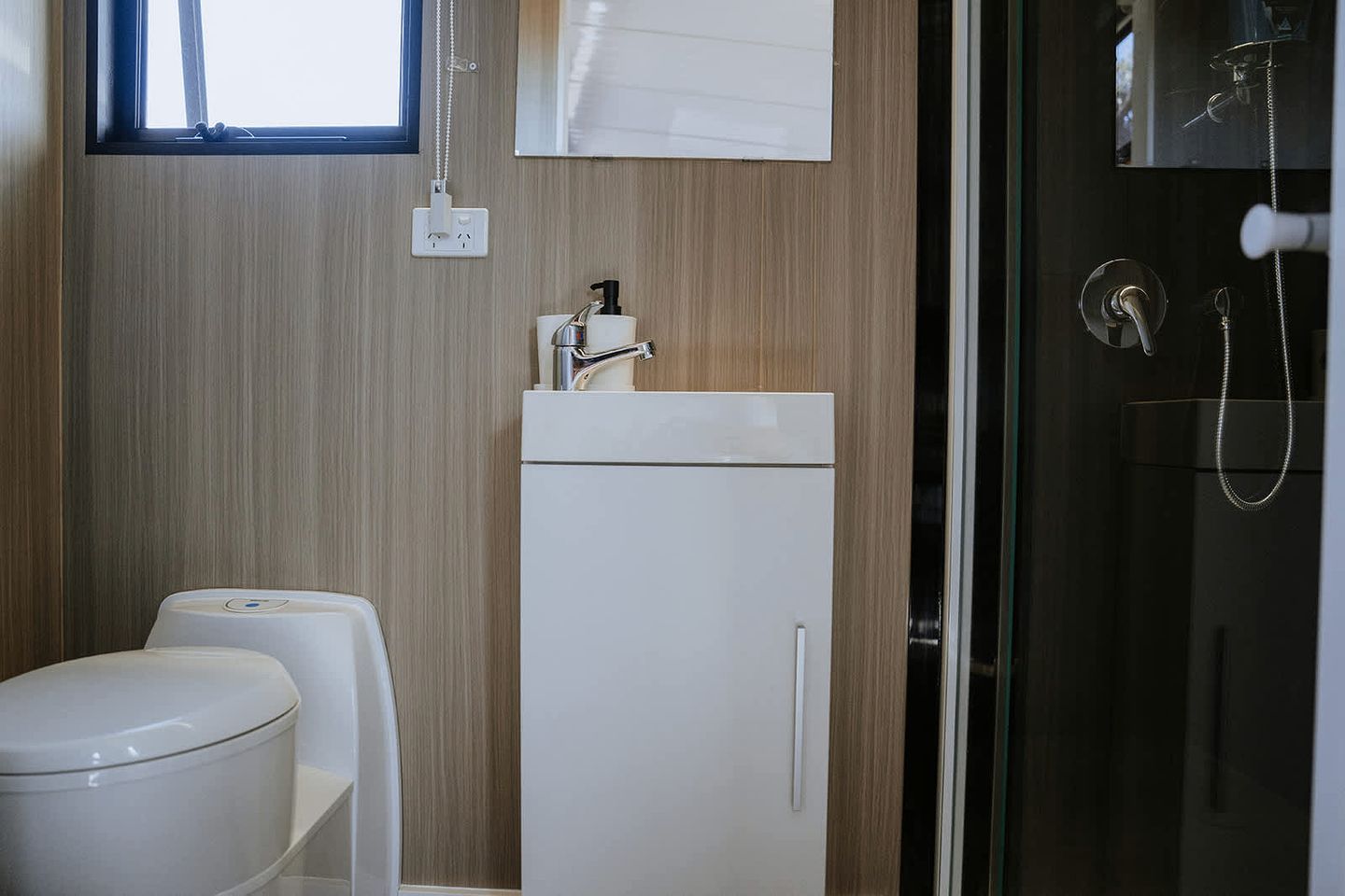 A compact bathroom with a toilet, a sink, and a shower area.