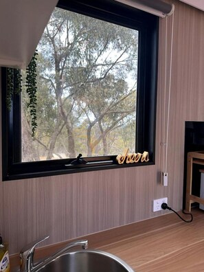 Una cocina con ventana, un lavabo y un armario de madera.