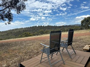 Un área de estar al aire libre con dos sillas y una mesa, con vistas a un paisaje montañoso.