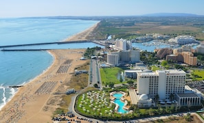 A coastal resort with a beach, a marina, and a pool area.