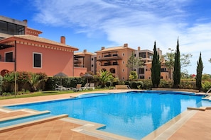 A swimming pool with a clear blue water surface, surrounded by a tiled deck.
