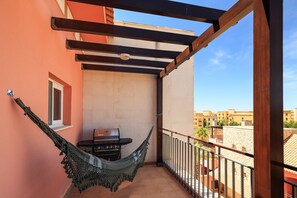 A balcony with a hammock, a grill, and a view of the cityscape. - Apartment 'Luxury 2 Bed Vilamoura Penthouse' with Shared Pool, Wi-Fi and Air Conditioning (Quarteira)
