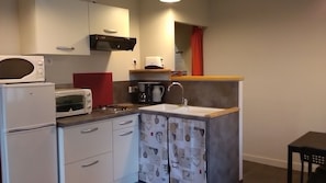 Cocina compacta con microondas, tostadora, cafetera y pileta.