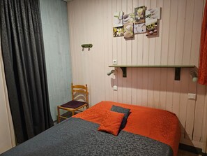 Una camera da letto con un letto, una sedia, una mensola e un pannello decorativo in legno sulla parete.