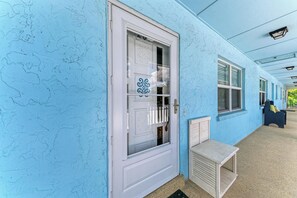 Um corredor com uma porta azul, um banco e uma janela com persianas.