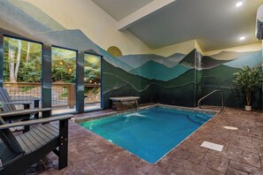 An indoor swimming pool with a mountain mural on the wall, seating area with chairs, and a view of the outdoors. - EVERSTONE Luxury Couples Retreat with Private Indoor Pool, Sauna & Hot Tub (Gatlinburg)