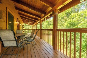 A wooden deck with outdoor seating and a view of a forest. - 🐻 Happy Bear | Arcade, Electric Fireplaces & Seasonal Community Pool (Sevierville)
