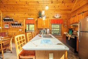 Ein Holzblockhaus-Innenraum mit Kücheninsel, Holzschränken und einem Kühlschrank.