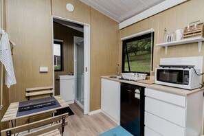 A compact kitchenette with a microwave, sink, and a small window. - Secluded Tiny House on Macadamia Plantation Near Byron Bay, Cumbalum NSW (Cumbalum)