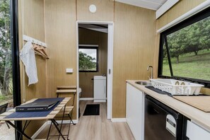 A compact kitchenette with a sink, a small window, and a view of greenery outside. - Secluded Tiny House on Macadamia Plantation Near Byron Bay, Cumbalum NSW (Cumbalum)