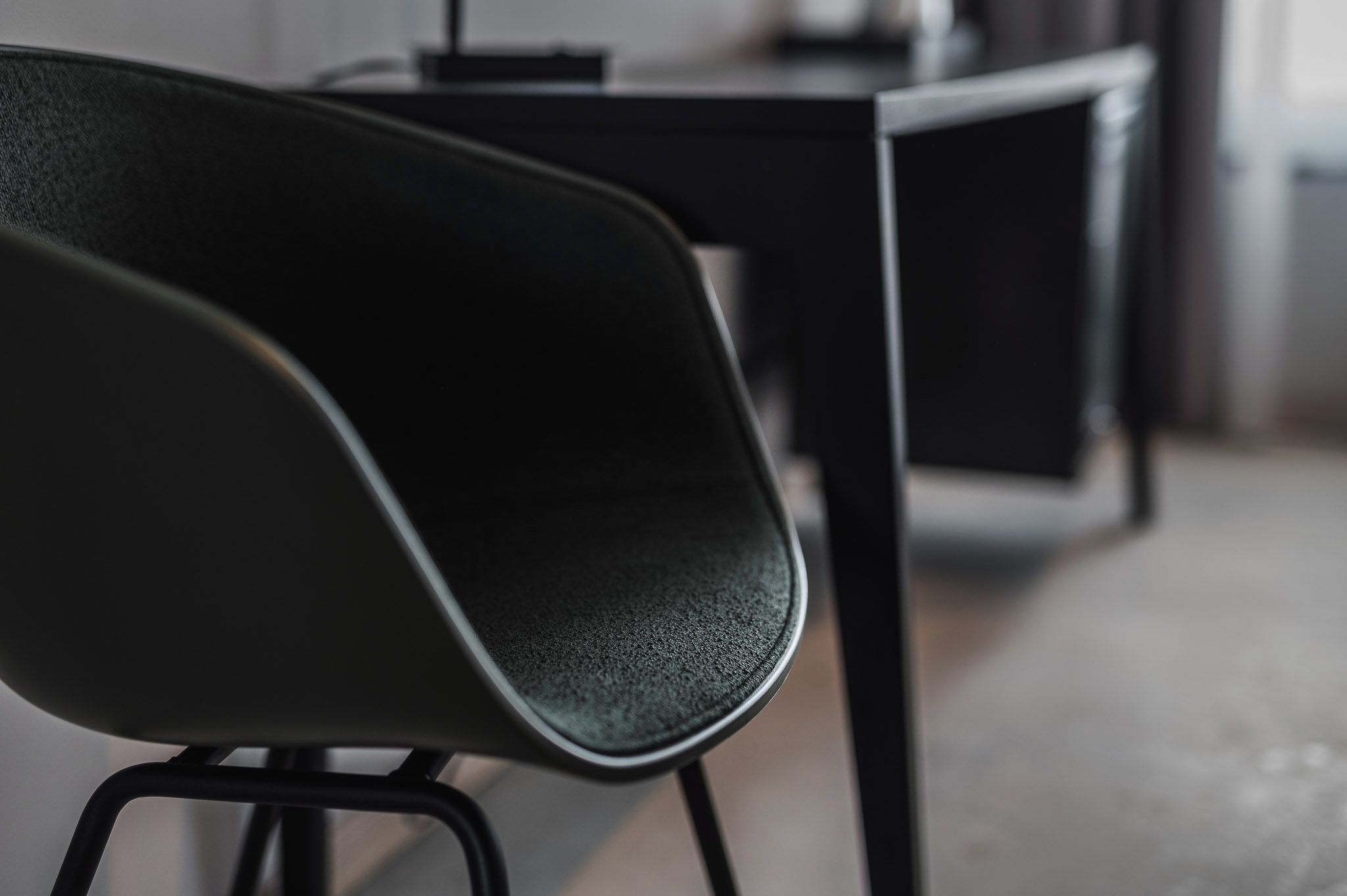 Primer plano de una silla negra con asiento texturizado y patas de metal.