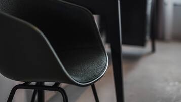 Primer plano de una silla negra con asiento texturizado y patas de metal.