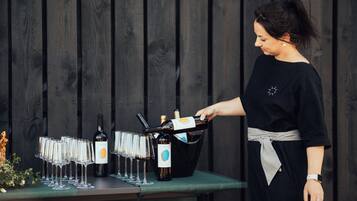 Una persona sirviendo champán en copas sobre una mesa con botellas y un cubo.