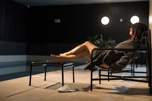 Una persona descansando en un banco junto a una piscina por la noche.
