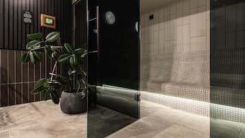 Um banheiro moderno com box de vidro, um vaso de planta e piso revestido de azulejos.