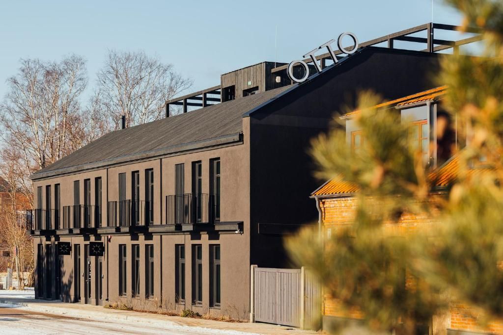 Een modern gebouw met een plat dak, grote ramen en een bord waarop 'OTTO' staat.