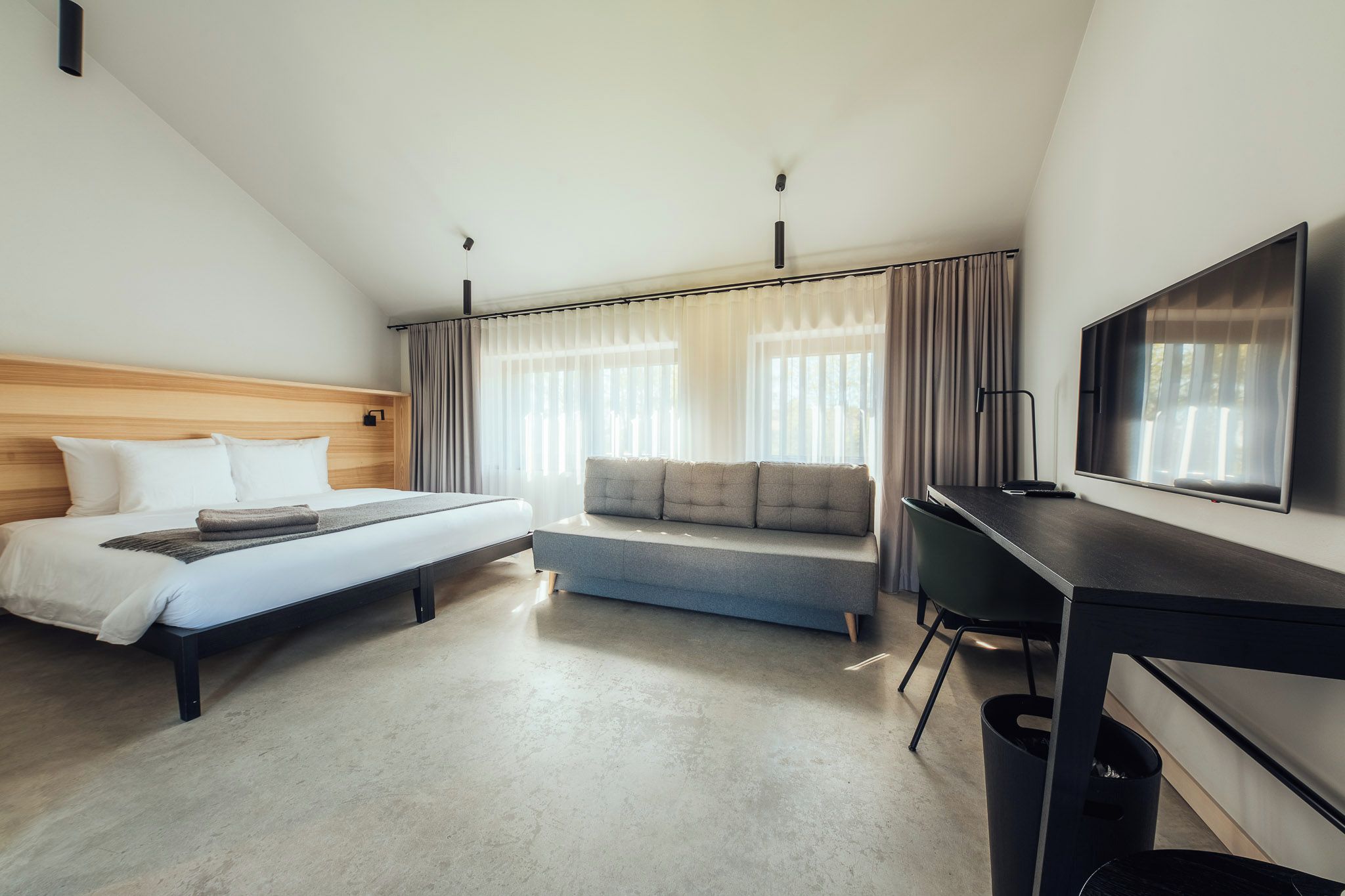 Een hotelkamer met een bed, een slaapbank, een bureau en een televisie.