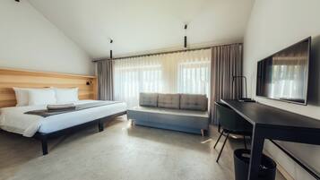 Een hotelkamer met een bed, een slaapbank, een bureau en een televisie.