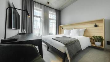 Een moderne hotelkamer met een bed, bureau, stoel en een kamerplant.