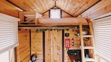 Un intérieur de cabine compact comprenant un lit en mezzanine, un coin cuisine et une petite salle de bain.