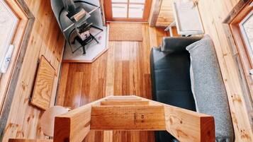Un intérieur compact en bois, avec un canapé, une petite table et une fenêtre.