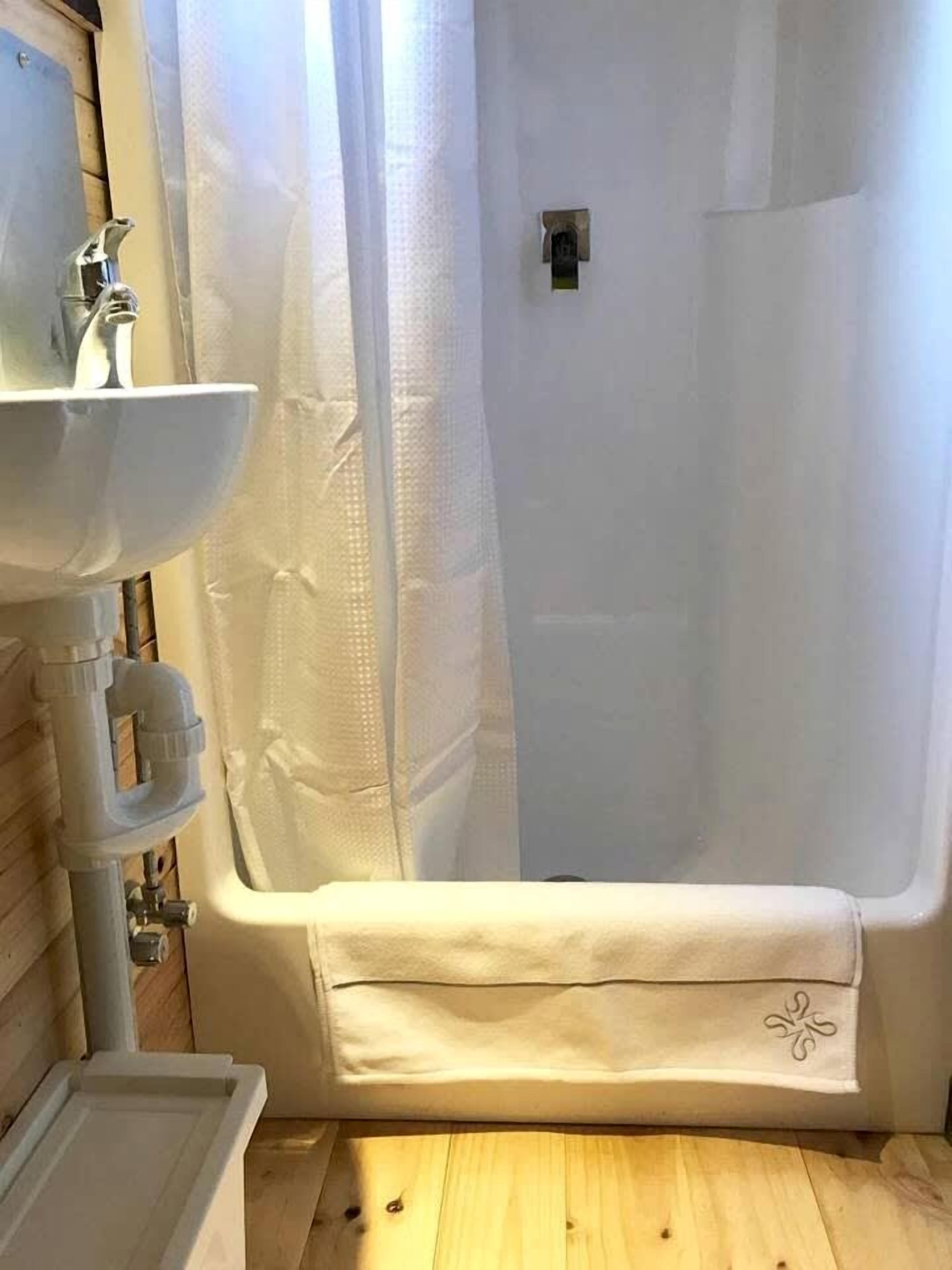 Een badkamer met een bad, een wastafel en een douchegordijn.