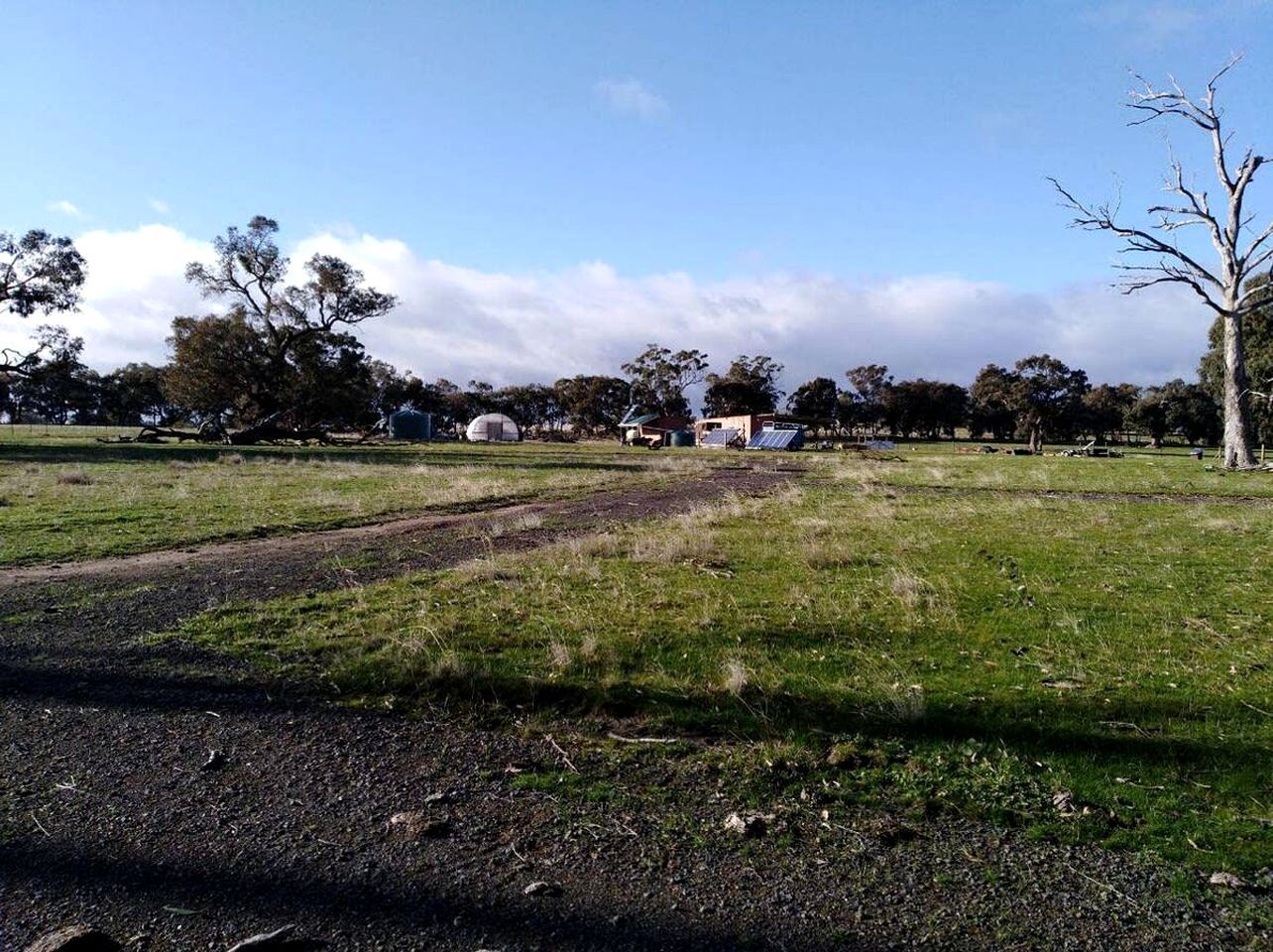 A grassy field with a dirt path leading to a building.