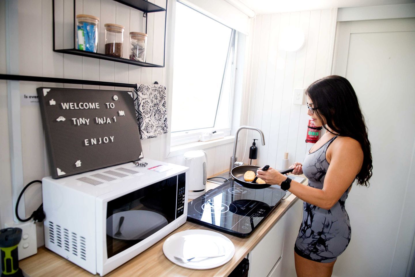 A kitchen with a microwave, a plate, and a person cooking.