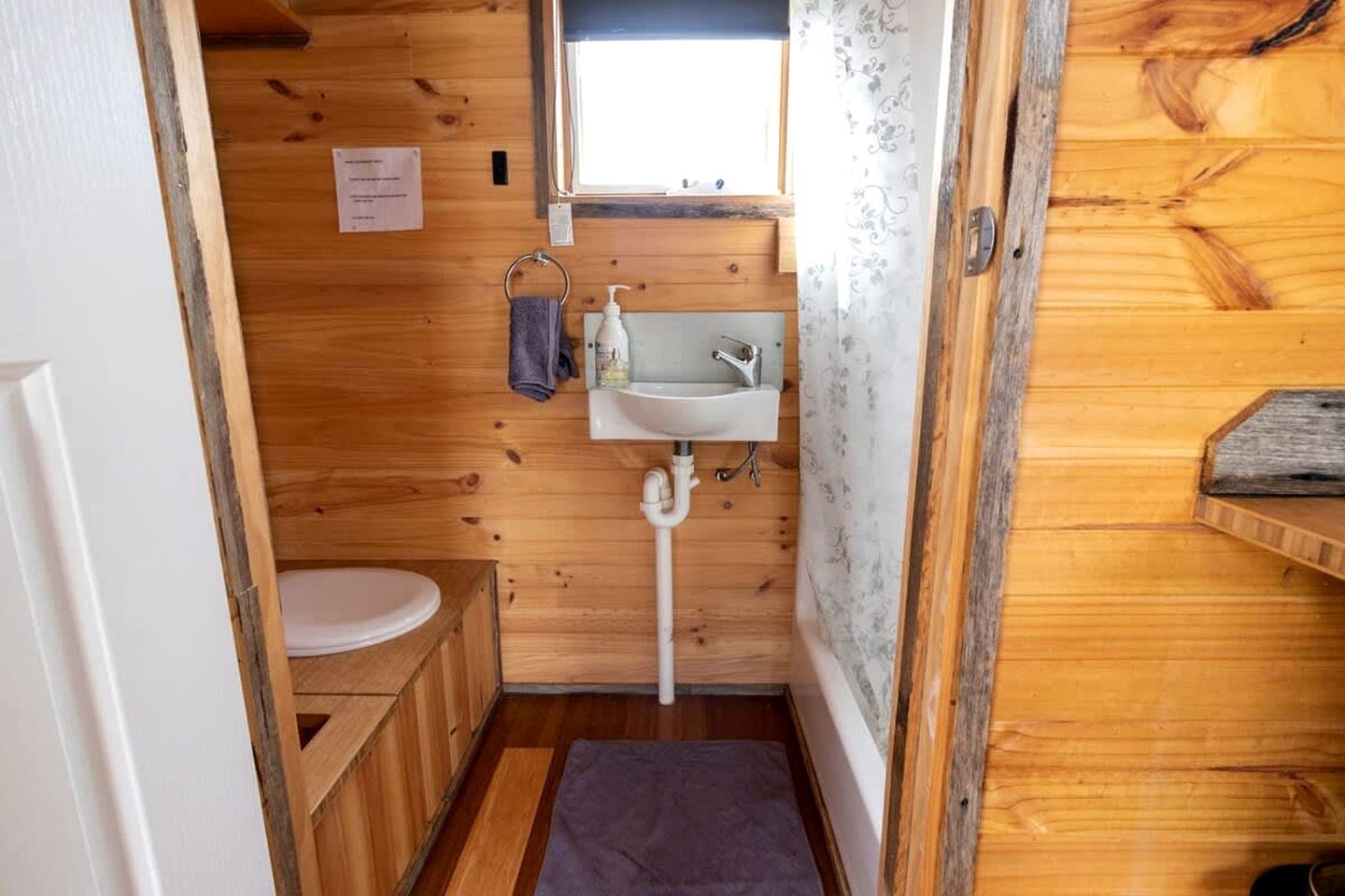Une petite salle de bain en bois, avec des toilettes, un lavabo et un espace douche.