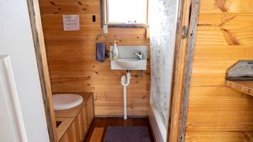 Une petite salle de bain en bois, avec des toilettes, un lavabo et un espace douche.