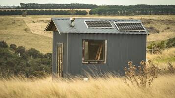 Un petit bâtiment d’un seul étage, doté d’un toit en pente, d’une fenêtre et de panneaux solaires sur le toit.