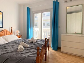 Ein Hotelzimmer mit einem Bett, einem Nachttisch, einer Kommode und einem Fenster mit Vorhängen.