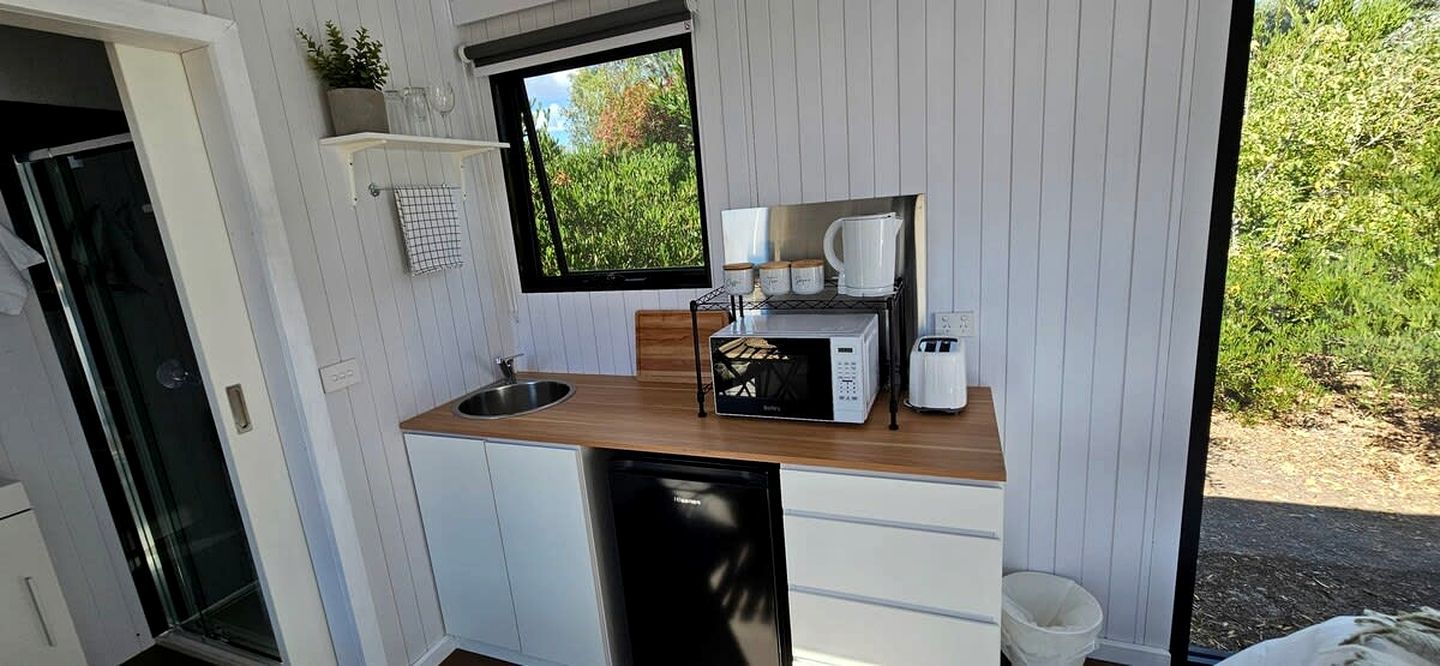 A compact kitchen with a sink, microwave, toaster, and a window with a view of greenery.