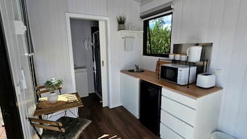 A compact kitchen with a microwave, sink, and a small dining area with a table and chair.