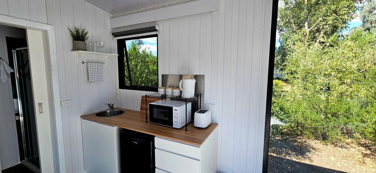 Cocina compacta con encimera de madera, microondas, tostadora y ventana con vistas a zonas verdes.