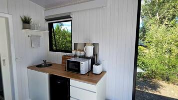 Cocina compacta con encimera de madera, microondas, tostadora y ventana con vistas a zonas verdes.
