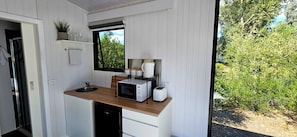 Una cucina compatta con un piano di lavoro in legno, un forno a microonde, un tostapane e una finestra vista verde.