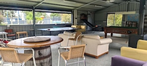 Un espacio recreativo interior con mesa de ping pong, mesa de billar y áreas de descanso que incluyen un sofá y sillas.