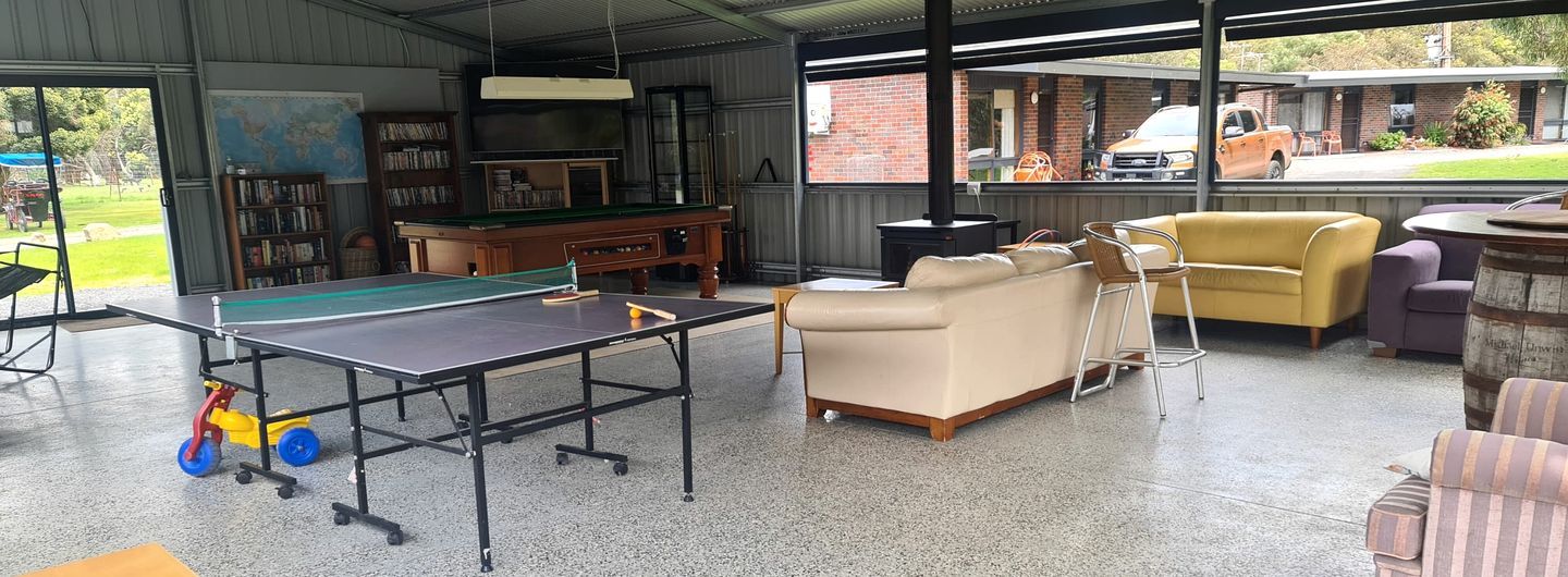 Una habitación con mesa de ping pong, un sofá, una silla, una estantería y una chimenea.