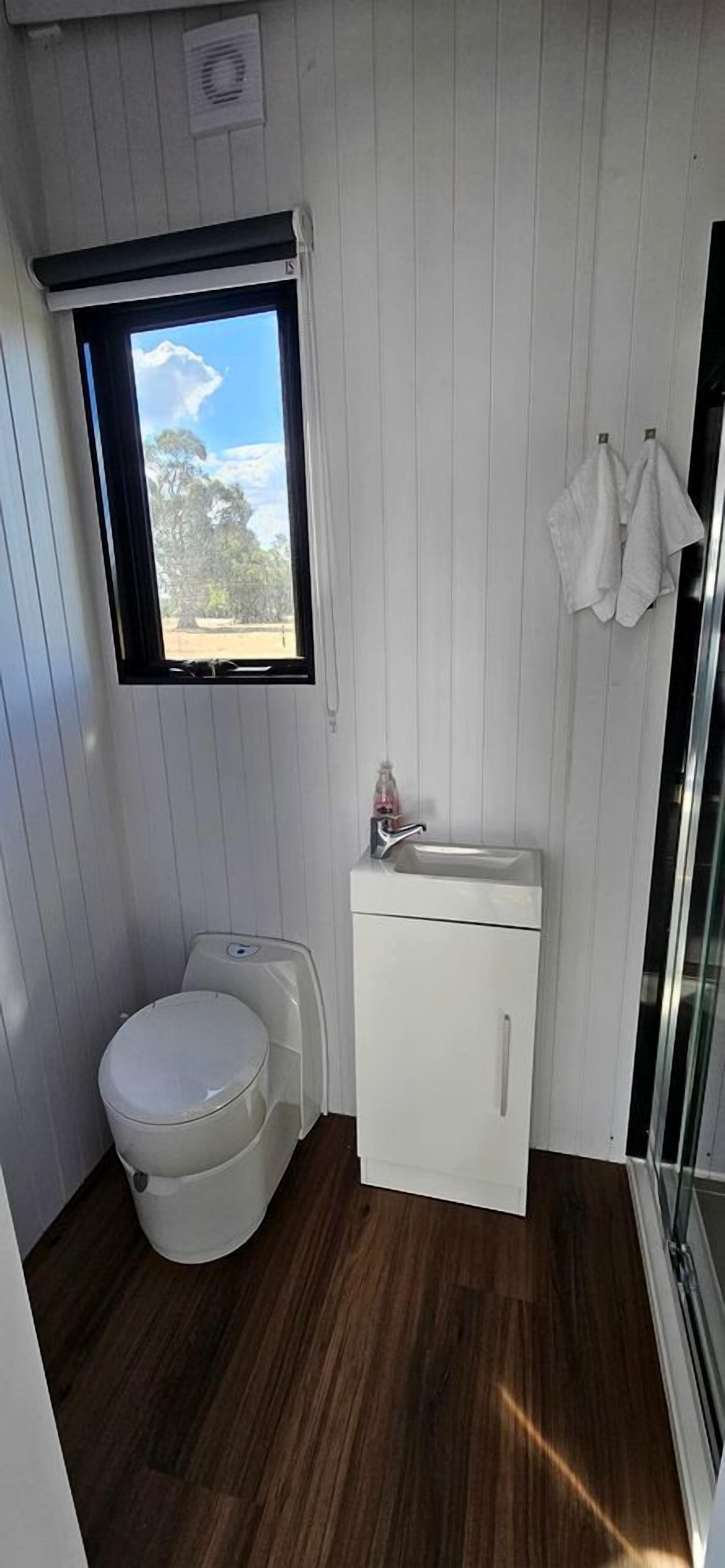 A compact bathroom with a toilet, a small sink, and a window.