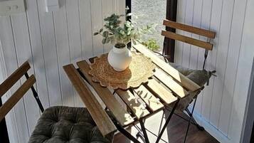 Una habitación con una mesa de madera y dos sillas, una planta encima de la mesa, y vistas al exterior.