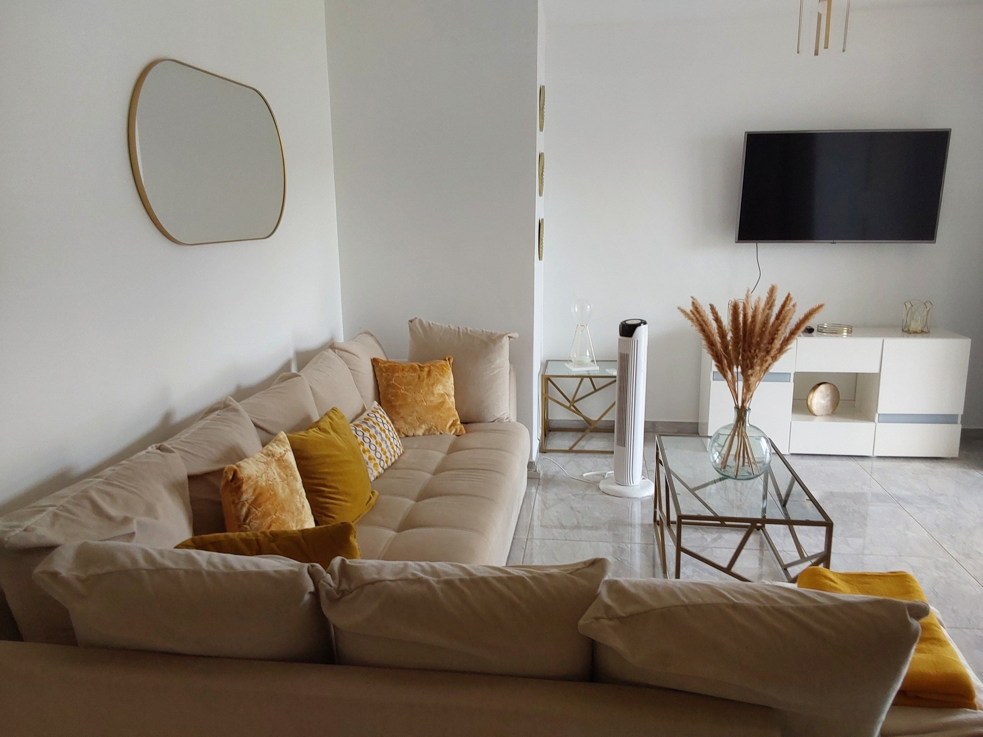 A modern living room with a sofa, a flat-screen TV, and a minimalist coffee table.