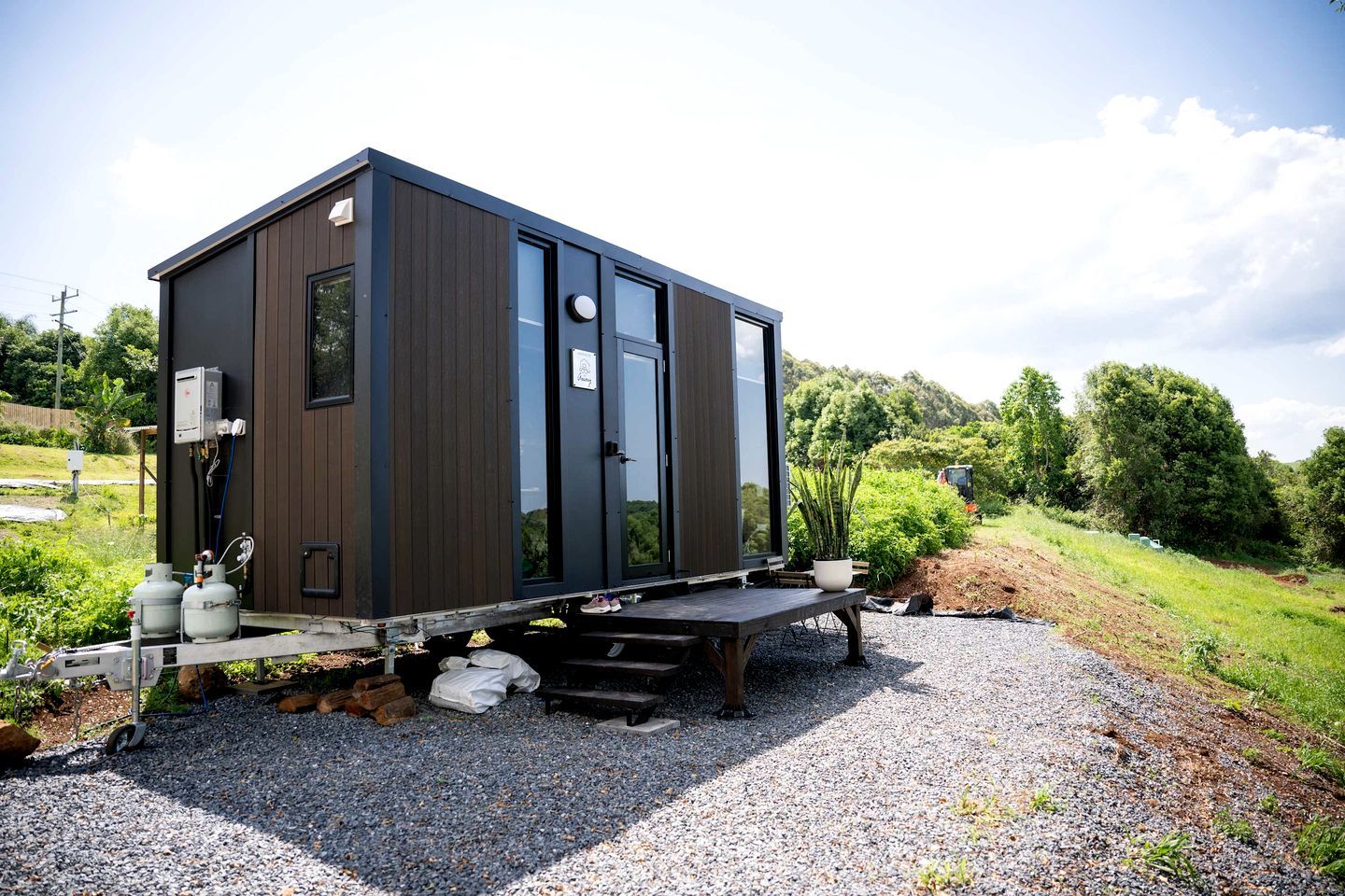 Una cabaña moderna y compacta con techo plano, ventanas amplias y un pequeño porche.