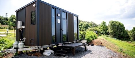 Una cabaña moderna y compacta con techo plano, ventanas amplias y un pequeño porche.